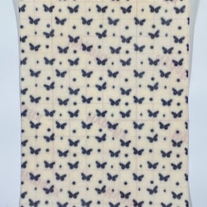 May include: A sheet of paper with a repeating pattern of dark blue butterflies and dots on a cream-colored background. The butterflies are evenly spaced in a grid-like arrangement. The paper is sealed in a clear plastic bag.