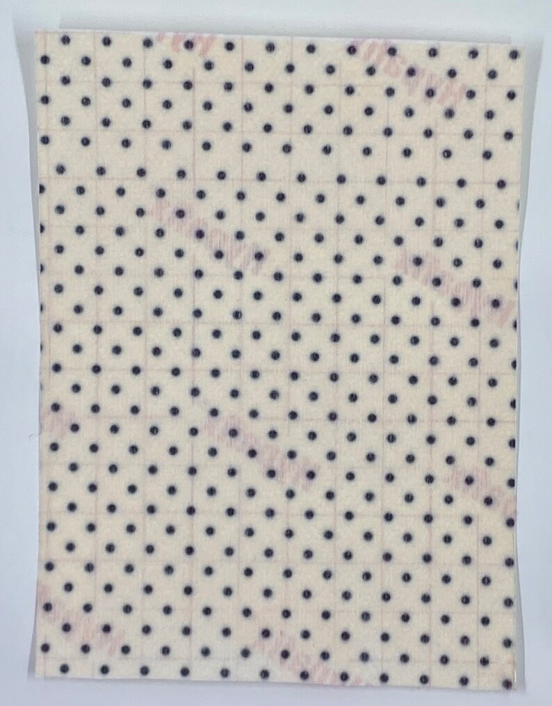 May include: A sheet of small, square stickers with a cream-colored background and evenly spaced dark blue polka dots. The stickers are arranged in a grid pattern, and the sheet is enclosed in a clear plastic sleeve.
