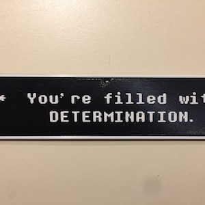 May include: A black and white sign with a white border that reads "* You're filled with DETERMINATION."