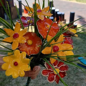 Könnte beinhalten: Ein Strauß aus Keramikblumen in Rot-, Orange- und Gelbtönen. Die Blumen sind zu einem Strauß gebunden und haben ein realistisches Aussehen.