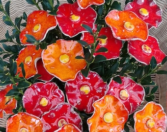 Può includere: Un bouquet di fiori in ceramica in tonalità arancio e rosso. I fiori hanno una superficie testurizzata e ondulata e sono disposti in un cesto.