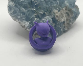 May include: Purple 3D printed Pokemon character charm featuring a purple and white design. The charm is in a circular frame.
