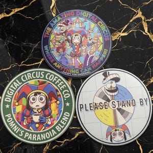 May include: Three circular stickers featuring The Amazing Digital Circus characters. One shows a circus scene with text, another depicts a character holding a coffee cup with text, and the third shows a test pattern with the text PLEASE STAND BY.