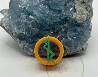 May include: A yellow and green circular emblem with a lightning bolt design. The emblem is set against a backdrop of a large, light blue crystal cluster. The emblem is a decorative item.