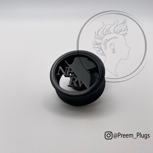 May include: Black ear plug with the word "NERV" cut out. The plug has a circular design with a silhouette. The Instagram handle "@Preem_Plugs" is in the bottom right corner.