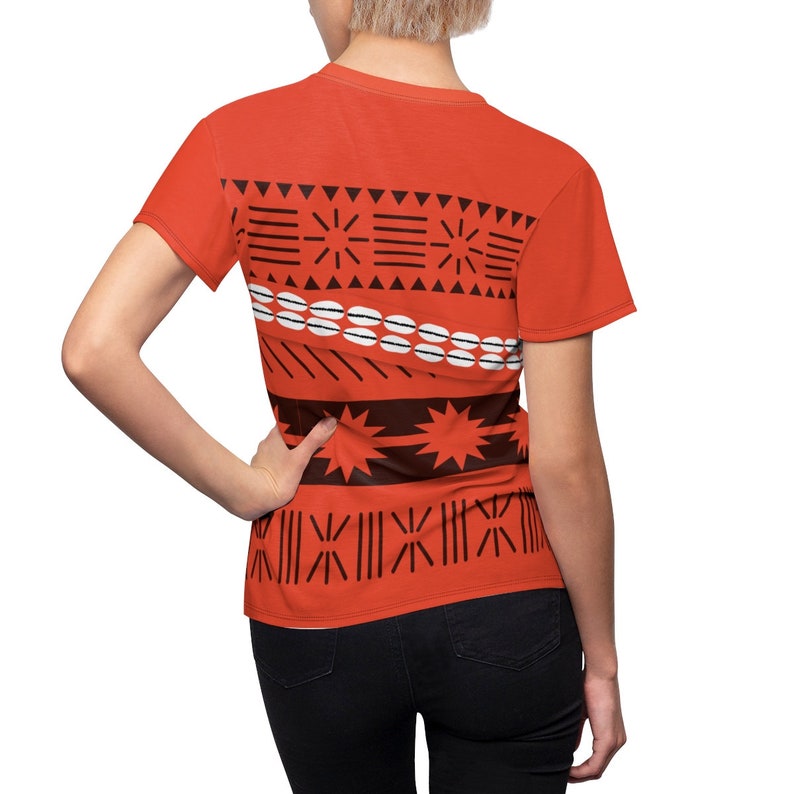 May include: A red t-shirt with a Polynesian-inspired pattern in black and white. The pattern features geometric shapes, stars, and a line of white circles.