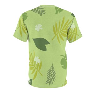 May include: A green short-sleeved t-shirt with a tropical leaf pattern. The leaves are in shades of green and yellow.