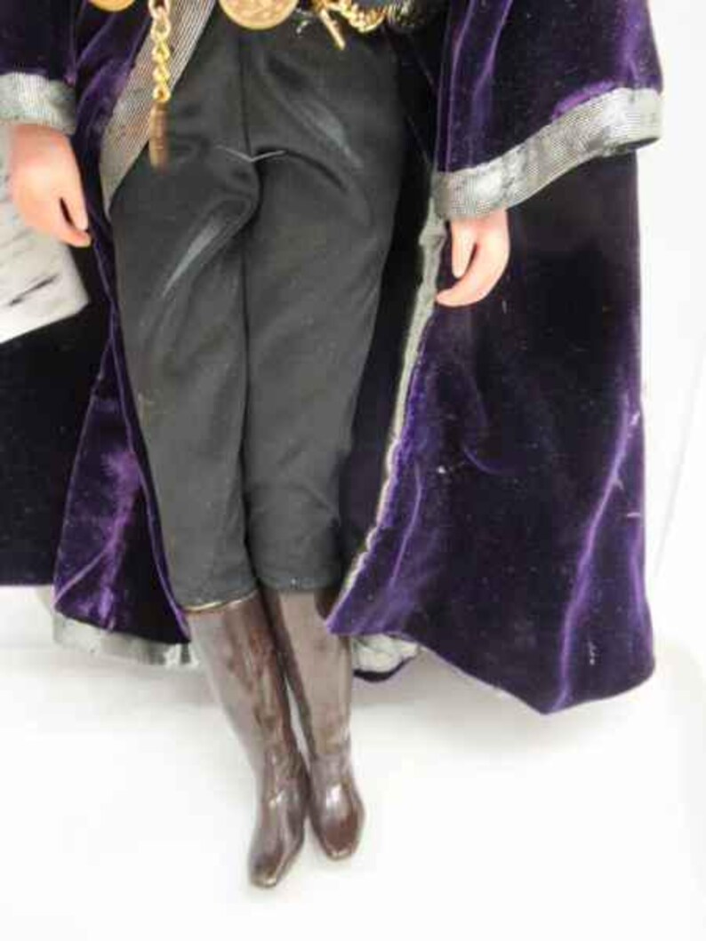 May include: A purple velvet robe with a silver trim and black pants with brown boots.