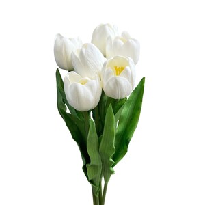May include: A bouquet of white tulips with green leaves. The tulips are arranged in a cluster, with the blooms facing outward.