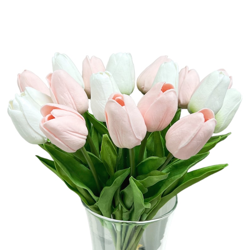 May include: A bouquet of pink and white artificial tulips in a clear glass vase. The tulips are arranged in a cluster with their stems extending out of the vase.