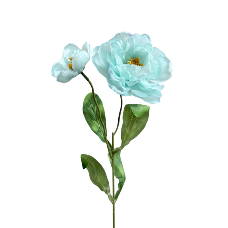 May include: A bouquet of two light blue artificial flowers with green leaves. The flowers have a delicate, ruffled appearance.