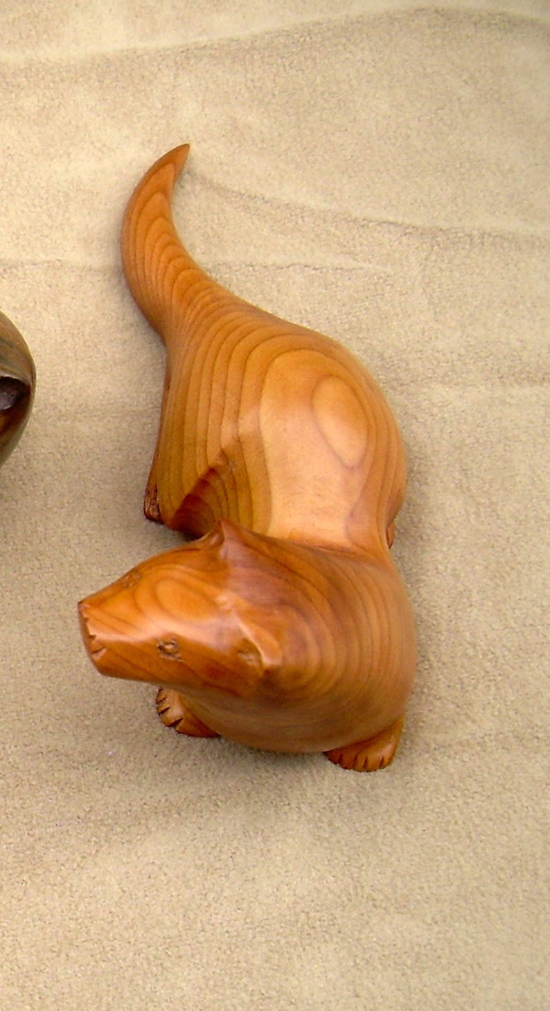 carved wooden otter in walnut. yew or spalted beech golden yew