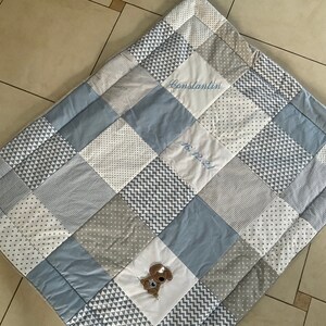 Peut inclure: Une courtepointe b&eacute;b&eacute; en patchwork bleu et gris avec un chien cousu et le nom "Constantin" et la date "16.12.2021".
