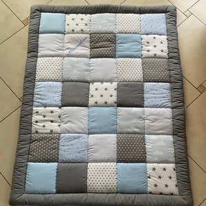 May include: A gray and blue patchwork play mat with a white star pattern and the name Maximilian embroidered on it.