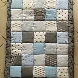 May include: A gray and blue patchwork baby playmat with a white embroidered name "Maximilian".