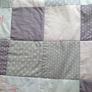 Pu&ograve; includere: Una trapunta patchwork con quadrati nei toni del rosa, grigio e bianco. Alcuni quadrati presentano testo ricamato, altri motivi a corona o a pois. La trapunta &egrave; un articolo morbido e fatto a mano.