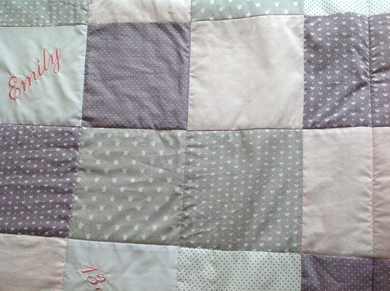 Pu&ograve; includere: Una trapunta patchwork con quadrati nei toni del rosa, grigio e bianco. Alcuni quadrati presentano testo ricamato, altri motivi a corona o a pois. La trapunta &egrave; un articolo morbido e fatto a mano.