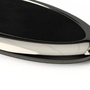 May include: A black oval-shaped tray with a silver rim and a silver decorative knob on the end.