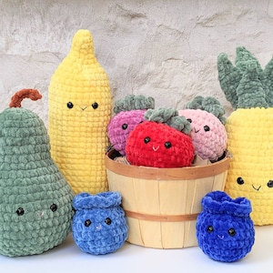 May include: A collection of crocheted plush fruit and vegetables, including a pear, banana, pineapple, strawberries, and blueberries. The fruit and vegetables are arranged in a wooden basket.
