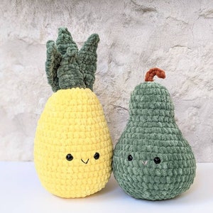 May include: Two plush crochet fruit toys: a yellow pineapple with green leaves and a green pear with a brown stem. Both have smiling faces with black eyes and a stitched mouth. The toys are made of soft, textured yarn.
