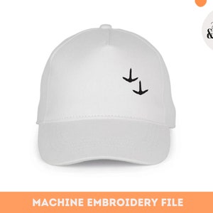 Può includere: Un cappellino da baseball bianco con visiera curva. Il cappellino presenta due piccole sagome di uccelli neri ricamate sul davanti. Il testo "MACHINE EMBROIDERY FILE" è visualizzato nella parte inferiore dell'immagine.