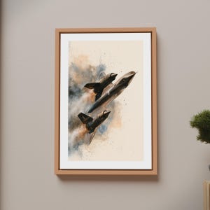 May include: A framed wall art print featuring a dark, sleek supersonic jet aircraft angled upward. The jet is surrounded by abstract, smoky watercolor splashes in shades of blue, brown, and gray against a light cream background.