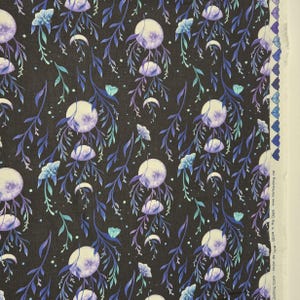 Könnte beinhalten: Schwarzer Stoff mit einem sich wiederholenden Muster aus Monden, Halbmonden, Blumen und Blättern in Lila, Blau und Türkis. Das Design ist vor einem schwarzen Hintergrund angeordnet und schafft ein himmlisches Thema.