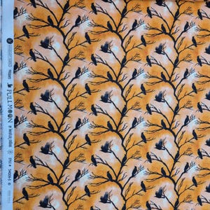 Könnte beinhalten: Stoff mit einem sich wiederholenden Muster aus schwarzen Krähen auf kahlen Ästen vor einem orange-weißen Hintergrund. Die Wörter "FULLMOON" und "WINDHAM FABRICS" sind auf der linken Seite aufgedruckt.