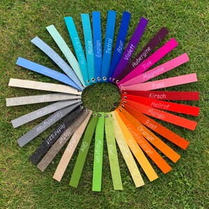 May include: A color chart with 24 felt swatches in a circle. The swatches are labeled with German words for colors, including Petrol, Enzian, Minze, Mint-T&uuml;rkis, Lindgr&uuml;n, Gletscher, Himmel, Hellgrau, Taubengrau, Natur, Anthrazit, Azur, Sahara, Oliv, Maigr&uuml;n, Violett, Aubergine, Pink, Magnolie, Ros&eacute;, Kirsch, Hellrot, Mango, Rost, Orange, Leuchtorange, Honig, Vanille, and Kiwi.