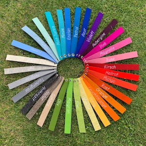 May include: A color chart with 24 felt swatches in a circle. The swatches are labeled with German words for colors, including Petrol, Enzian, Minze, Mint-T&uuml;rkis, Lindgr&uuml;n, Gletscher, Himmel, Hellgrau, Taubengrau, Natur, Anthrazit, Azur, Sahara, Oliv, Maigr&uuml;n, Violett, Aubergine, Pink, Magnolie, Ros&eacute;, Kirsch, Hellrot, Mango, Rost, Orange, Leuchtorange, Honig, Vanille, and Kiwi.