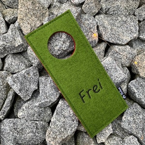 May include: Green felt door hanger with a round hole in the center and the word "Frei" embroidered in black thread.