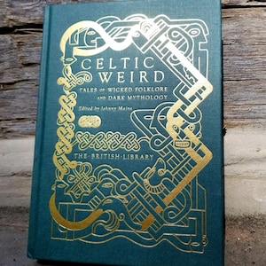 Puede incluir: Un libro de tapa dura verde azulado con un diseño de nudo celta dorado en la portada. El título "Celtic Weird" está escrito en letras doradas. El subtítulo es "Tales of Wicked Folklore and Dark Mythology." El libro está publicado por The British Library.