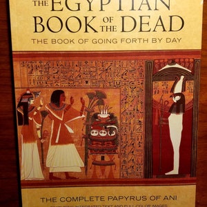 May include: The cover of a book titled "The Egyptian Book of the Dead: The Book of Going Forth by Day." The cover features a colourful illustration of ancient Egyptian hieroglyphics, figures, and symbols. The book is a revised edition and includes the complete papyrus of Ani.