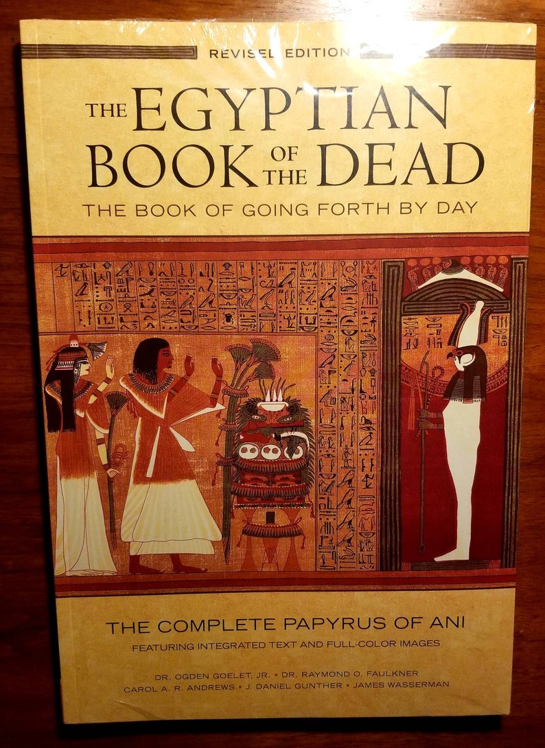 May include: The cover of a book titled "The Egyptian Book of the Dead: The Book of Going Forth by Day." The cover features a colourful illustration of ancient Egyptian hieroglyphics, figures, and symbols. The book is a revised edition and includes the complete papyrus of Ani.