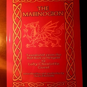 Puede incluir: La portada de un libro rojo titulado "The Mabinogion" con un borde de nudo celta dorado y una ilustración de un dragón rojo. El libro está traducido del Red Book of Hergest por Lady Charlotte Guest. La introducción y las notas al pie son de Owen Edwards.