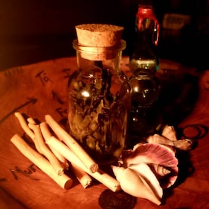 May include: Two glass bottles with cork stoppers, one with a red wax seal, on a wooden surface with a circular design and writing. The bottles are filled with a dark liquid and there are seashells and sticks on the surface.