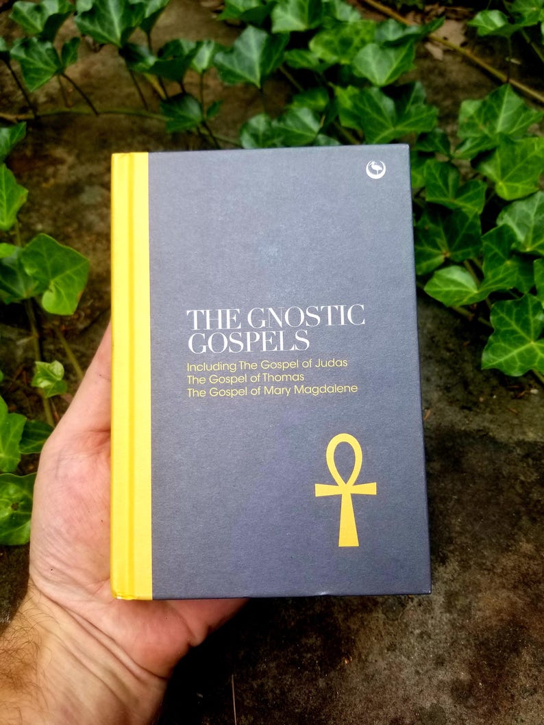 May include: A dark gray book with a yellow spine and the title "The Gnostic Gospels" printed in white. The book includes the Gospel of Judas, the Gospel of Thomas, and the Gospel of Mary Magdalene. A yellow ankh symbol is printed on the front cover.