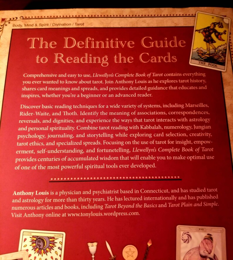 May include: The Definitive Guide to Reading the Cards book cover features a red background with gold text. The book title is "The Definitive Guide to Reading the Cards". The author is Anthony Louis. The book cover also features a tarot card image of "The Fool".