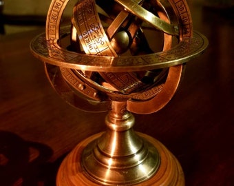 May include: A brass celestial globe with a wooden base. The globe is marked with the zodiac signs and degrees. The globe is on a wooden base.