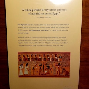 May include: The back cover of a book about the Papyrus of Ani, an ancient Egyptian philosophical and religious text. The cover features a quote from Library Journal, a detailed description of the book, and a colourful illustration of a scene from the Papyrus of Ani.