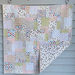 May include: A patchwork quilt with a variety of colorful patterns, including polka dots, flowers, and geometric shapes. The quilt is made of cotton fabric and is quilted with a simple stitch.