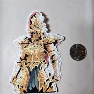 May include: A sticker of a golden knight wearing armor with a large, spiky helmet. The knight is standing with its arms at its sides. The sticker is on a white background.