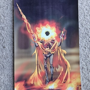 May include: An artistic print depicting a skeletal figure with a flaming head and a golden cape. The figure holds a staff and a knife, standing amidst flames. The artwork features a dark, ominous background with fiery hues.