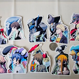 May include: A set of 12 colourful stickers featuring anime characters and their personas. The stickers are printed on white glossy paper and have a rounded rectangular shape.