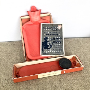 May include: A red rubber hot water bottle in a box with a pamphlet for a Belladonna Plaster. The pamphlet has the text "The Heat Treatment You Want. Belladonna Plaster. Fast Relief from Backache."