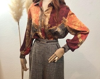 May include: A long-sleeved, patterned blouse with a button-up collar and a brown and white houndstooth skirt.