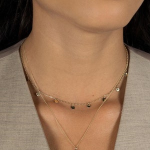 Model poses wearing Lavey London's Solid 9ct Gold Circle Drop Charm Choker Necklace and Large Hammered Disc Pendant
