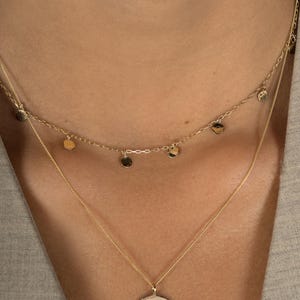 Close up shot of neck modelling Lavey London's solid 9ct gold drop charm choker and large hammered disc pendant necklace