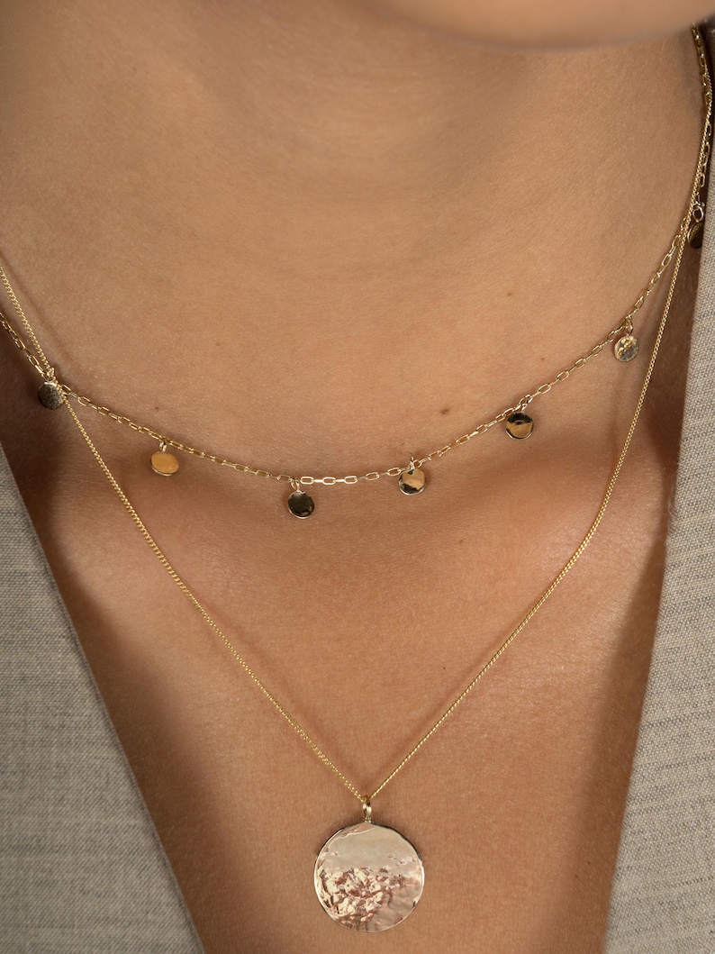 Close up shot of neck modelling Lavey London's solid 9ct gold drop charm choker and large hammered disc pendant necklace