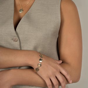 Up close shot of model wearing Lavey London's Solid 9ct Gold Hammered Disc Bracelet, Drop Charm Choker and Large Hammered Disc Pendant